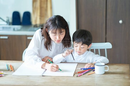 Photo for Mother and child studying with pencils and notebook in the room - Royalty Free Image