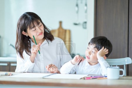 Téléchargez les photos : Mère et enfant étudient avec des crayons et un cahier dans la chambre - en image libre de droit