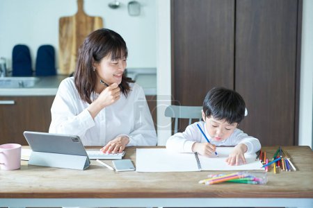 Téléchargez les photos : Une mère travaillant dans sa chambre et un enfant dessinant - en image libre de droit