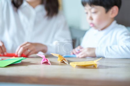 Téléchargez les photos : Parent et enfant jouant avec origami dans la chambre - en image libre de droit