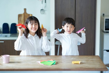 Téléchargez les photos : Parent et enfant jouant avec origami dans la chambre - en image libre de droit