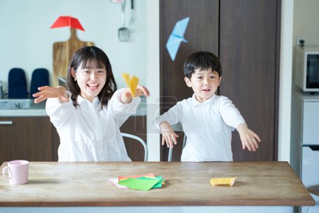 Photo for Parent and child playing with origami in the room - Royalty Free Image