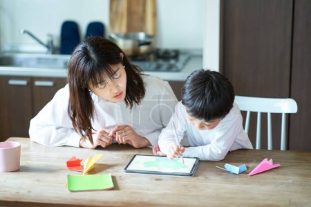 Téléchargez les photos : Mère et enfant jouant avec une tablette PC dans la chambre - en image libre de droit
