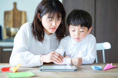 Téléchargez les photos : Mère et enfant jouant avec une tablette PC dans la chambre - en image libre de droit