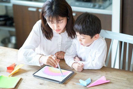 Photo for Mother and child playing with a tablet PC in the room - Royalty Free Image