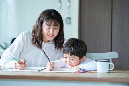 Foto de Madre e hijo estudiando con lápices y cuaderno en la habitación - Imagen libre de derechos