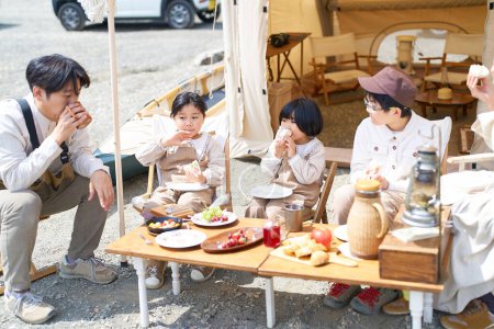 Téléchargez les photos : Une famille de cinq personnes dégustant un repas dans un camping - en image libre de droit