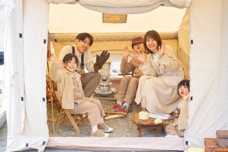 Téléchargez les photos : Une famille joyeusement relaxante dans une tente - en image libre de droit