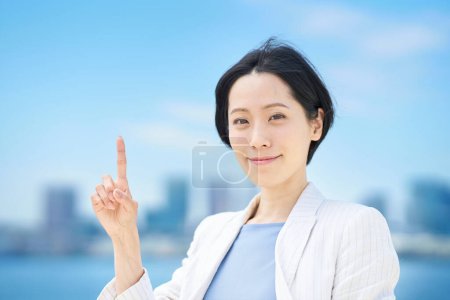Téléchargez les photos : Femme d'affaires posant pour lever le doigt le beau jour - en image libre de droit