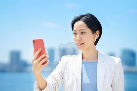 Téléchargez les photos : Femme d'affaires avec smartphone en plein air par temps ensoleillé - en image libre de droit