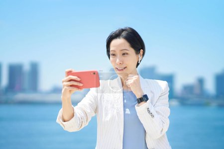 Téléchargez les photos : Femme d'affaires acclamant tout en regardant l'écran du smartphone - en image libre de droit