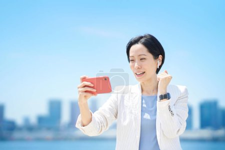 Téléchargez les photos : Femme d'affaires acclamant tout en regardant l'écran du smartphone - en image libre de droit