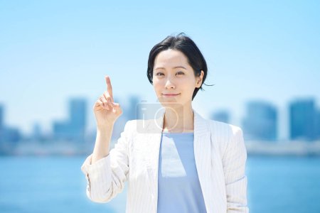 Photo for Business woman posing pointing upwards on fine day - Royalty Free Image