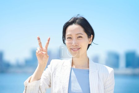 Téléchargez les photos : Femme d'affaires faisant un signe de paix avec un sourire le beau jour - en image libre de droit
