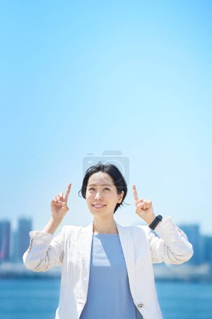 Téléchargez les photos : Femme d'affaires posant pointant vers le haut le beau jour - en image libre de droit