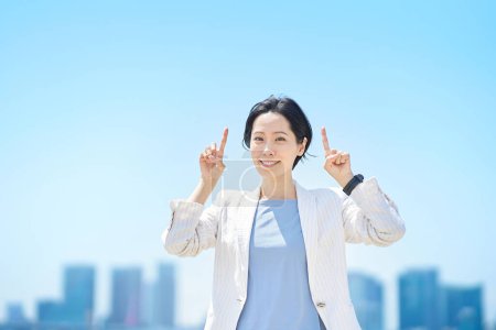 Photo for Business woman posing pointing upwards on fine day - Royalty Free Image