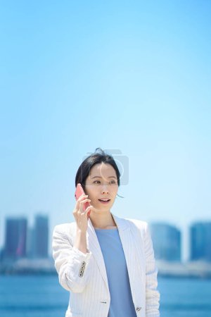 Téléchargez les photos : Femme d'affaires parlant sur smartphone le beau jour - en image libre de droit