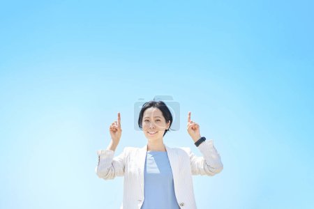 Téléchargez les photos : Femme d'affaires posant pointant vers le haut le beau jour - en image libre de droit