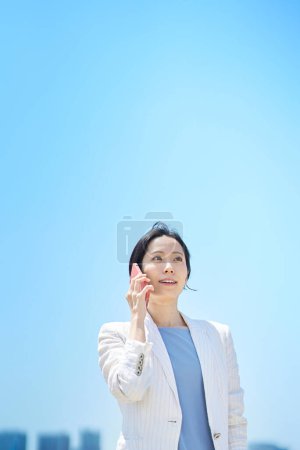 Photo for Business woman talking on smartphone on fine day - Royalty Free Image