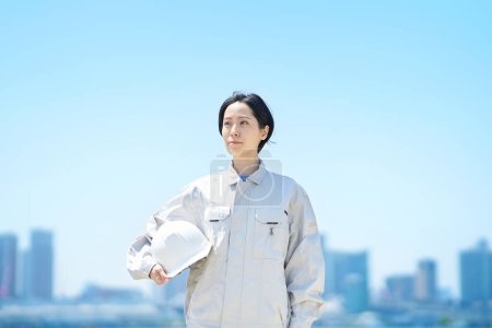 Photo for A woman in work clothes holding a helmet on fine day - Royalty Free Image