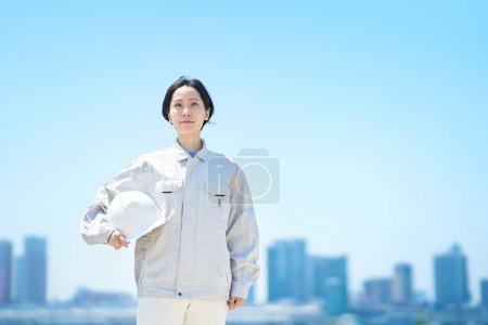 Téléchargez les photos : Une femme en vêtements de travail tenant un casque le beau jour - en image libre de droit