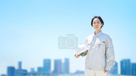 Photo for A woman in work clothes holding a helmet on fine day - Royalty Free Image