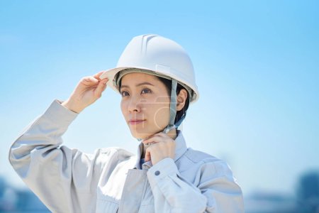 Foto de Una mujer vestida con ropa de trabajo y revisando un casco en un buen día - Imagen libre de derechos