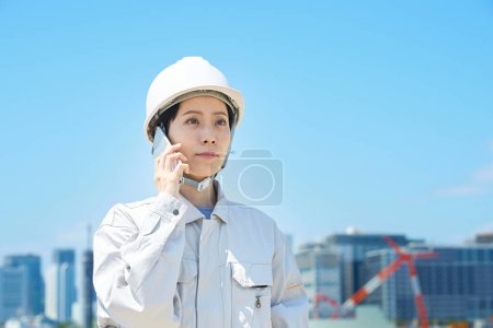 Téléchargez les photos : Une femme en vêtements de travail parlant sur un smartphone le beau jour - en image libre de droit