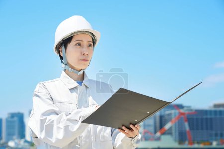 Téléchargez les photos : Une femme en vêtements de travail vérifiant le site le beau jour - en image libre de droit