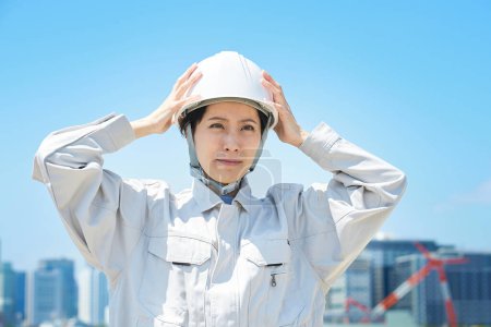 Téléchargez les photos : Une femme en vêtements de travail tenant sa tête à l'extérieur - en image libre de droit