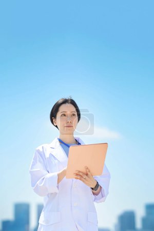 Téléchargez les photos : Une femme en manteau blanc tenant un dossier le beau jour - en image libre de droit
