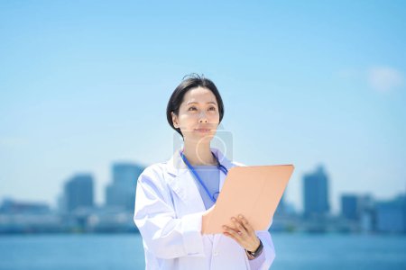 Photo for A woman in a white coat holding a file on fine day - Royalty Free Image