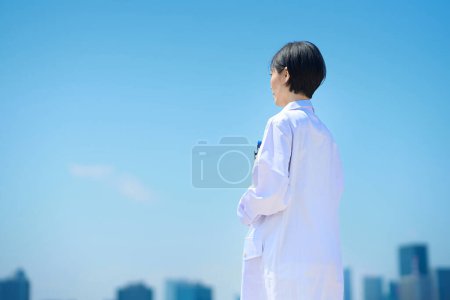 Photo for Back view of a woman in a white coat on fine day - Royalty Free Image