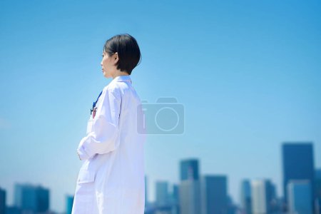 Photo for Back view of a woman in a white coat on fine day - Royalty Free Image