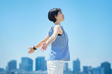 Téléchargez les photos : Une femme avec une expression détendue sous le ciel bleu - en image libre de droit