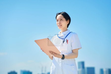 Photo for A woman in a white coat with a file outdoors - Royalty Free Image