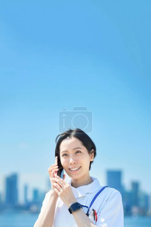 Téléchargez les photos : Une femme en manteau blanc tenant un smartphone à l'extérieur - en image libre de droit