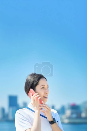 Foto de Una mujer con un abrigo blanco sosteniendo un teléfono inteligente al aire libre - Imagen libre de derechos