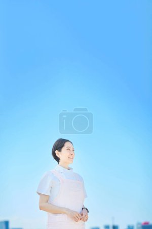 Téléchargez les photos : Femme portant un manteau blanc et un tablier à l'extérieur - en image libre de droit