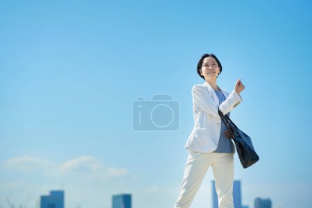 Téléchargez les photos : Femme d'affaires en costume navettant sous le ciel bleu - en image libre de droit