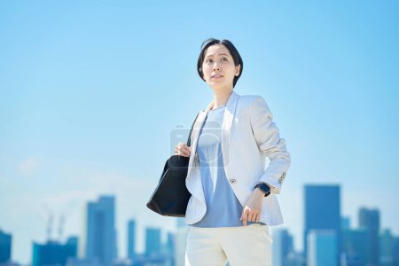 Photo for Business woman in suit commuting under the blue sky - Royalty Free Image