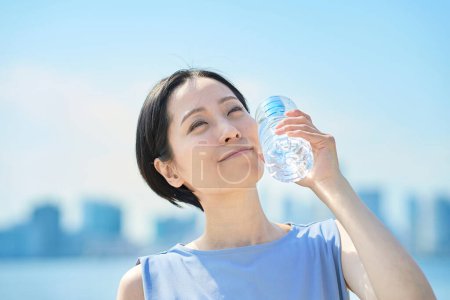 Photo for Woman drinking water from a plastic bottle outdoors - Royalty Free Image