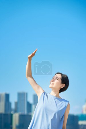 Photo for A woman blocking the strong sunlight under the blue sky on fine day - Royalty Free Image