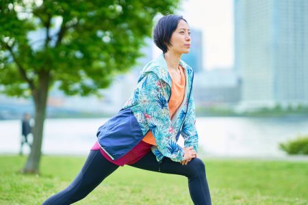Photo for Asian woman exercising on urban green space - Royalty Free Image