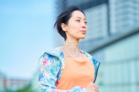 Photo for Asian woman running on urban green space - Royalty Free Image