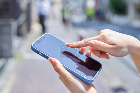 Téléchargez les photos : Main d'une femme utilisant un smartphone dans un coin de rue - en image libre de droit