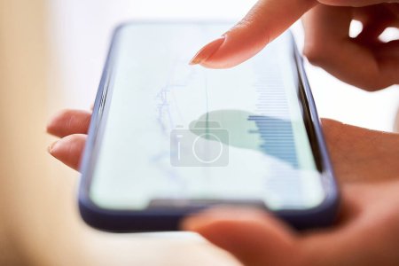 Téléchargez les photos : Une main de femme vérifie le tableau d'échange sur son smartphone dans la chambre - en image libre de droit