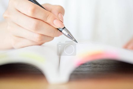 Foto de Primer plano de la mano de una mujer estudiando con texto - Imagen libre de derechos