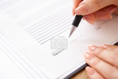 Foto de Mano de mujer firmando un documento con pluma - Imagen libre de derechos