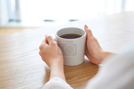 Foto de La mano de una mujer sosteniendo una taza y pensando en la habitación - Imagen libre de derechos